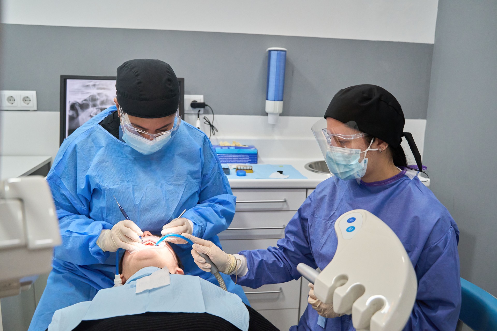 Dentists performing dental procedure on patient in clinic