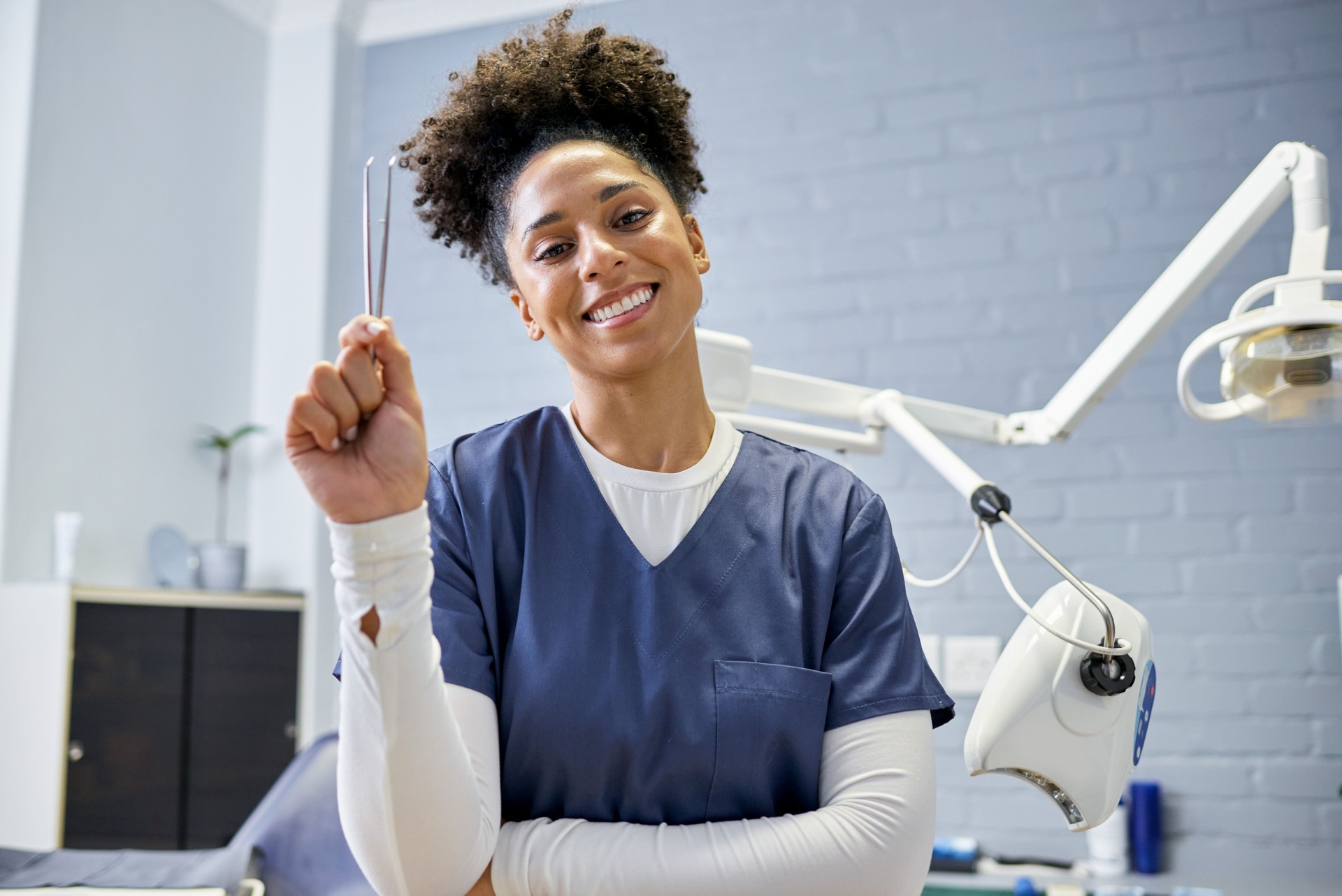 Smiling Dental Professional Holding Dental Tool in Modern Clinic Setting